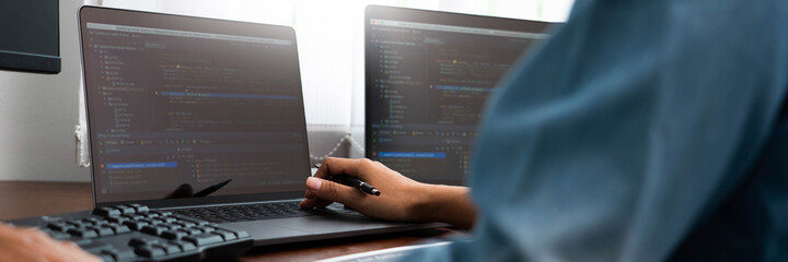 Programmer or software developer Typing New Lines of Code, coding technologies working at wooden industrial interior work place station.
