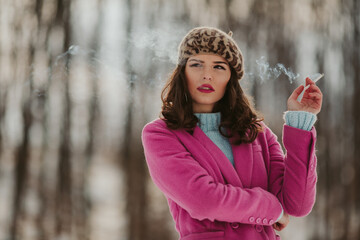 Poster - Woman wearing a pink coat with a beret and smoking a cigarette in a forest