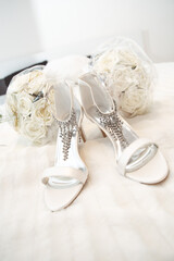 Poster - Closeup shot of beautiful bridal shoes with a bouquet on the bed