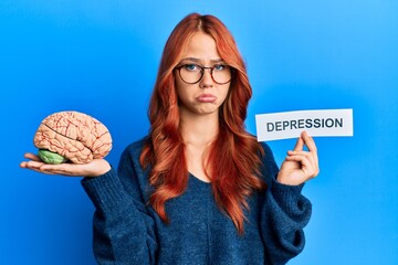 Sticker - Young redhead woman holding brain and depression text depressed and worry for distress, crying angry and afraid. sad expression.