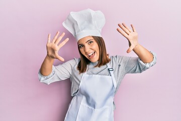 Poster - Young beautiful woman wearing professional cook uniform and hat showing and pointing up with fingers number ten while smiling confident and happy.