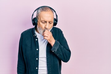 Poster - Handsome senior man with beard listening to music using headphones feeling unwell and coughing as symptom for cold or bronchitis. health care concept.