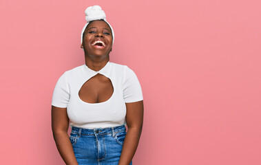 Wall Mural - Young african woman with turban wearing hair turban over isolated background smiling and laughing hard out loud because funny crazy joke with hands on body.