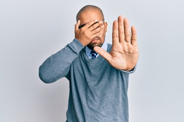 Poster - Hispanic adult man wearing glasses and business style covering eyes with hands and doing stop gesture with sad and fear expression. embarrassed and negative concept.