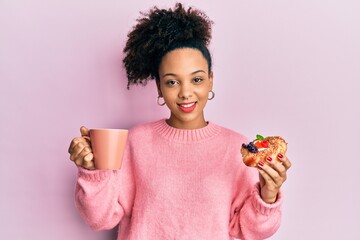 Poster - Young african american girl drinking a cup of coffee and eating sweet smiling with a happy and cool smile on face. showing teeth.