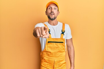 Wall Mural - Young handsome man wearing handyman uniform over yellow background pointing displeased and frustrated to the camera, angry and furious with you