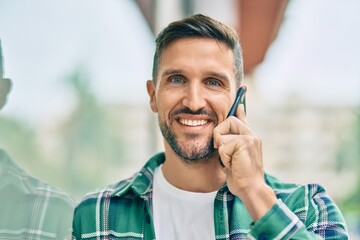 Wall Mural - Young caucasian man smiling happy talking on the smartphone at the city.