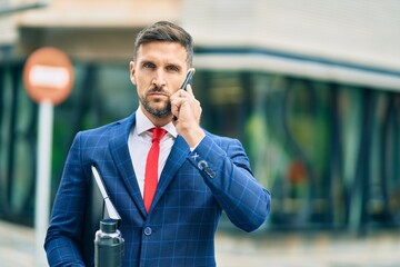 Poster - Young caucasian businessman with serious expression talking on the smartphone at the city.