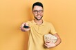 © Krakenimages.com - Young hispanic man eating popcorn using tv control winking looking at the camera with sexy expression, cheerful and happy face.