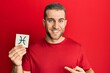 © Krakenimages.com - Young caucasian man holding paper with pisces zodiac sign pointing finger to one self smiling happy and proud