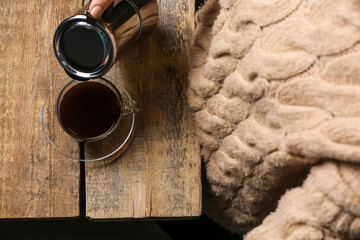 Woman pouring hot coffee into cup on wooden table