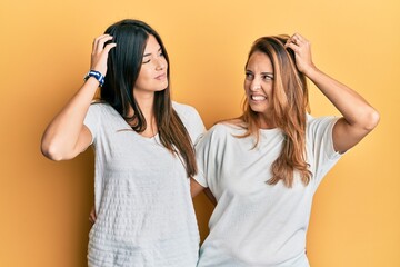 Wall Mural - Hispanic family of mother and daughter wearing casual white tshirt confuse and wondering about question. uncertain with doubt, thinking with hand on head. pensive concept.