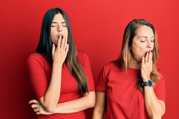 Canvas Print - Hispanic family of mother and daughter wearing casual clothes over red background bored yawning tired covering mouth with hand. restless and sleepiness.