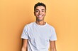 © Krakenimages.com - Young handsome african american man wearing casual white tshirt looking positive and happy standing and smiling with a confident smile showing teeth