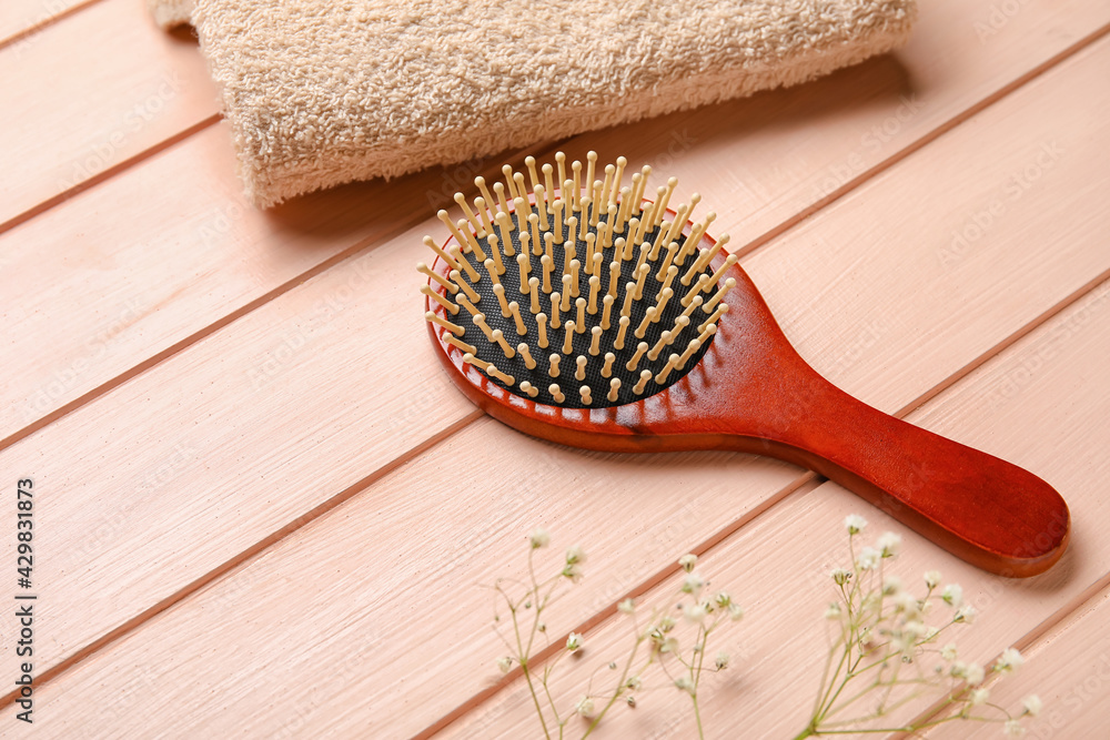 Hair brush with towel on wooden background