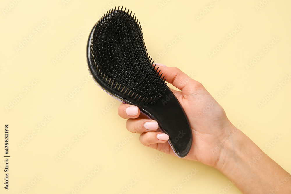 Female hand with plastic hair brush on light background