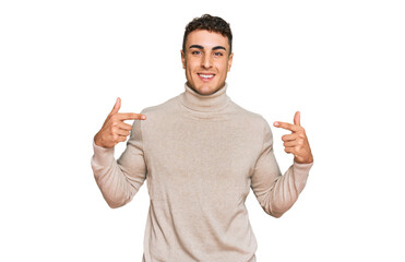 Hispanic young man wearing casual turtleneck sweater looking confident with smile on face, pointing oneself with fingers proud and happy.