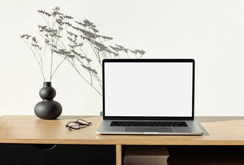 Laptop computer with empty blank mockup screen over white modern living room design. Work place, home office interior. Business, web site advertisement, workspace concept