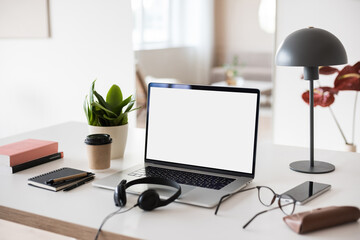 Laptop computer with empty blank mockup screen over white modern living room design. Home office, workplace, working or studying from home, distance learning, business concept
