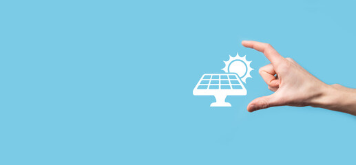 Wall Mural - Hand on a blue background holds the icon symbol of solar panels. Renewable energy, solar panels station concept, green electricity