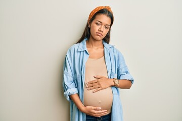 Sticker - Beautiful hispanic woman expecting a baby, touching pregnant belly looking sleepy and tired, exhausted for fatigue and hangover, lazy eyes in the morning.