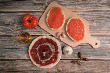 Wall Mural - Breakfast of bread toasts with acorn-fed Iberian ham, tomato, garlic and olive oil (tumaca bread) on dark gray background