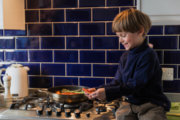 Happy blond boy, 4-5 years old, helps in cooking. Seafood.