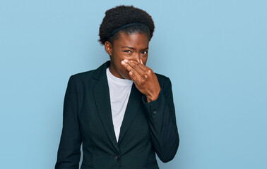 Sticker - Young african american girl wearing business clothes smelling something stinky and disgusting, intolerable smell, holding breath with fingers on nose. bad smell