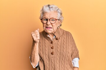 Wall Mural - Senior grey-haired woman wearing casual clothes and glasses angry and mad raising fist frustrated and furious while shouting with anger. rage and aggressive concept.