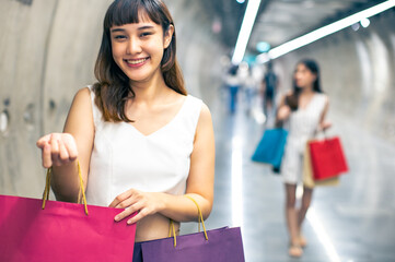 Asian woman wearing face mask. Happy woman with shopping bags enjoying in shopping. Girl holding colour paper bag.Friends walking in shopping mall.time shopping coronavirus crisis or covid19 outbreak