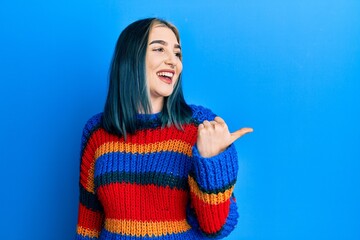 Wall Mural - Young modern girl wearing casual white t shirt pointing thumb up to the side smiling happy with open mouth