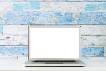 Wall Mural - An open laptop on a white desk. Mockup. A wall made of old blue boards.