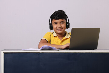 Indian syudent or kid attending online school using computer studying using laptop. 