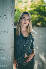 Sticker - Young Caucasian woman with green eyes leaning on the wall with graffitis