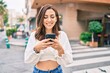 © Krakenimages.com - Young hispanic woman smiling happy using smartphone at the city.