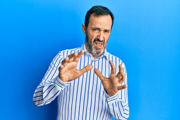 Poster - Middle age hispanic man wearing casual clothes afraid and terrified with fear expression stop gesture with hands, shouting in shock. panic concept.