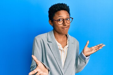 Wall Mural - Young african american girl wearing business jacket and glasses clueless and confused expression with arms and hands raised. doubt concept.