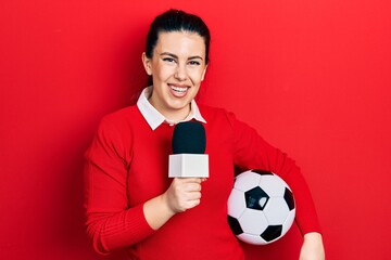 Sticker - Young hispanic woman holding reporter microphone and soccer ball smiling with a happy and cool smile on face. showing teeth.