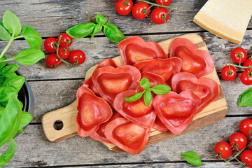 Poster - Red heart ravioli with tomato, mozzarella and basil on a wood background