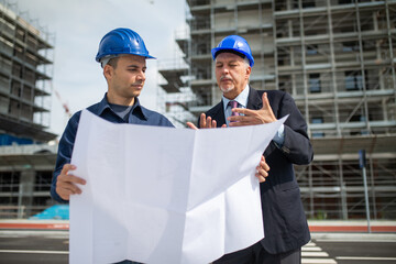 Wall Mural - Architect talking to the site manager in front of a construction site building