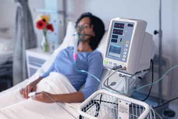 Wall Mural - Ventilator monitor and african american female patient in hospital bed with oxygen ventilator