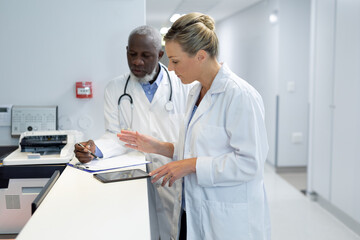 Diverse male and female doctors standing in hospital corridor looking at medical chart document