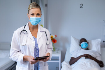 Wall Mural - Portrait of caucasian female doctor wearing face mask standing next to male patient