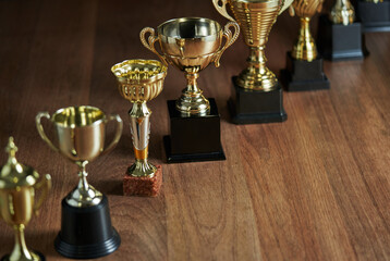 Poster - row of trophy on the wooden table against dark gray background