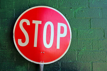 Traffic stop sign leaning on brick wall