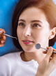 © rogerphoto - Smiling brunette woman being examined by dentist at sunny dental clinic. Hands of a doctor holding dental instruments near patient's mouth. Healthy teeth and medicine concept