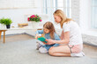 © галина шарапова - Happy caucasian mom with her daughter reading a book and smiling