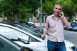 © JackF - Adult man is talking by phone and standing near his modern car outdoor.