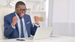 © stockbakers - Winning, African Businessman Celebrating Success on Laptop