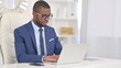 © stockbakers - Attractive Young African Businessman Working on Laptop in Office